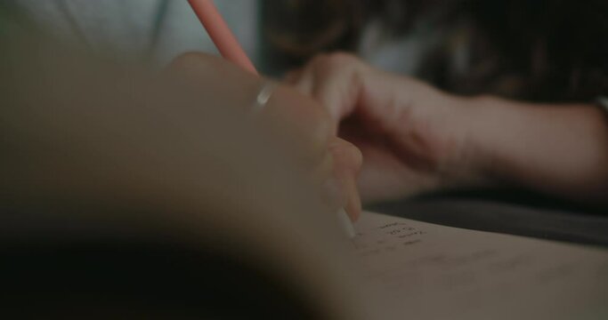 Soft focus background broll shot of student make notes in paper notebook during online class. Female hands write in notepad with pen, new ideas or plans for projects