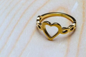 gold ring with a heart, a symbol of love and marriage, on a wooden background