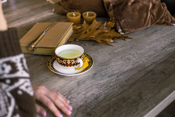Person sitting drinking tea and reading or writing a book in a calm and cozy environment. Concept of leisure time and relaxation.