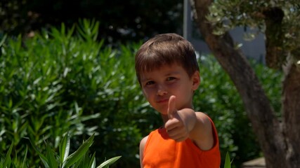 The little boy in the orange t-shirt shows a big thumb with approval