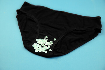 Concept of abnormal green vaginal discharge, signs of STD like trich. Black panties with green glitter.