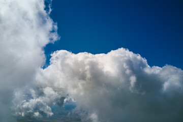 Aerial view from airplane window at high altitude of earth covered with white puffy cumulus clouds