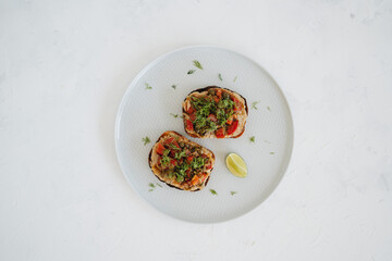 Eggplant toasts on a plate on white background