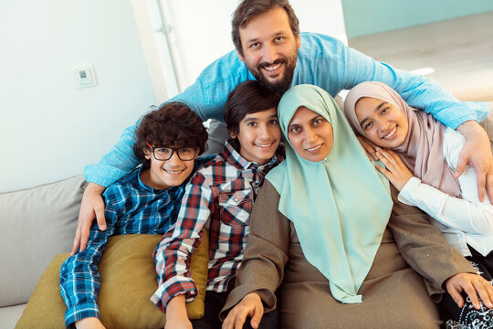 Portrait photo of an arab muslim family sitting on a couch in the living room of a large modern house. Selective focus 