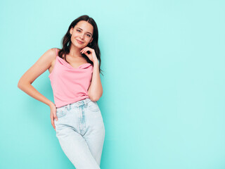 Young beautiful smiling female in trendy summer clothes. Sexy carefree woman posing near blue wall in studio. Positive brunette model having fun and going crazy. Cheerful and happy