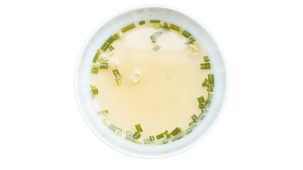 Above view of Hot broth sprinkled with chopped green onions and coriander. Inside white cup. On isolated white background with clipping path.