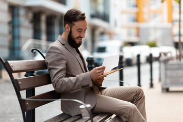 Good news in a letter. A happy man sits on a bench and reads an announcement about winning the...