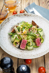 salad with tuna and cucumbers on a background with tea and cutlery
