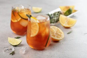 Iced tea with lemon, lime and ice garnished with rosemary twigs.