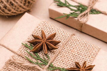 Festive decoration of gifts in eco-style.Gift boxes are wrapped in craft paper,tied with cotton thread,decorated with thuja leaves and badian,close-up.Christmas,New Year and eco-friendly concept.