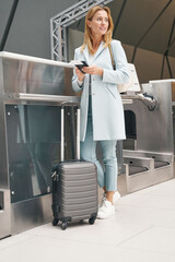 Female passenger standing at self-service bag drop