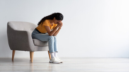 Despair Concept. Portrait Of Depressed Woman Sitting In Armchair At Home