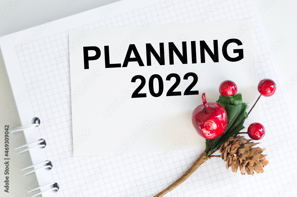 Poster a white card with the text planning 2022 on notepad on light background