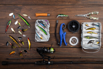 Fishing tackle - fishing spinning rod, hooks and lures on wooden background. Active hobby...
