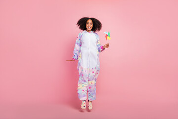 Full size photo of youth pretty african woman hold windmill origami paper jump isolated over pink color background