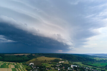 Landscape of dark clouds forming on stormy sky during thunderstorm over rural area