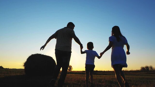 Silhouette happy family. Parents and little son fun at sunset. Silhouette family play at sunset. Teamwork child and parents fun in the park. Friendly family and kid dream concept.