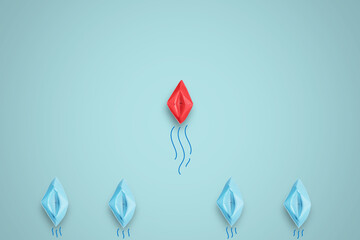 Fototapeta premium Red paper boat in front of line from blue ships in sea for leadership concept.