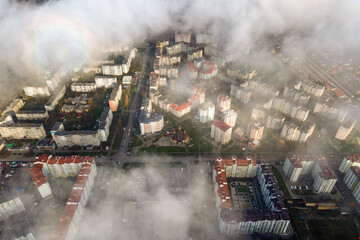 Top aerial view of fluffy white clouds over modern city with high rise buildings