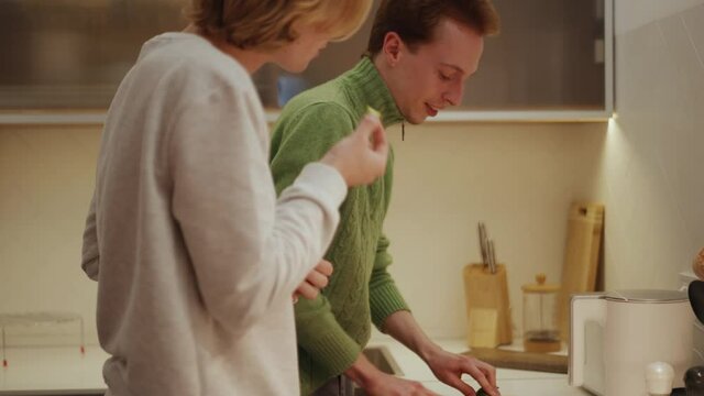 Positive gay couple cooking in kitchen