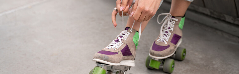 partial view of woman tying laces on roller skate, banner.