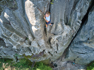 Young child boy climbing steep wall of rocky mountain. Kid climber overcomes challenging route....