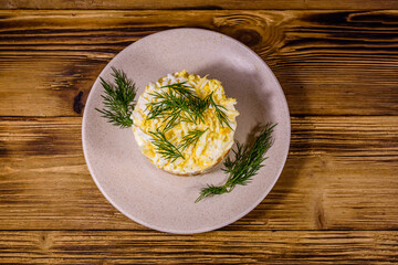 Salad with chicken breast, marinated mushrooms, carrot, eggs, boiled potato and mayonnaise on a wooden table. Top view