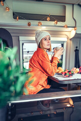 Thoughtful woman having breakfast in a camper van in the morning