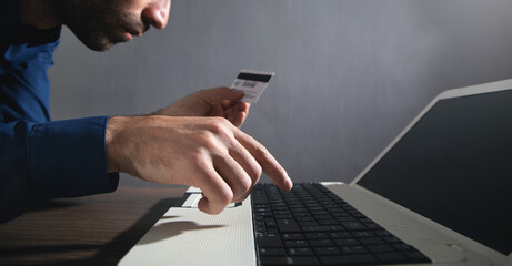Businessman using laptop computer and holding credit card.