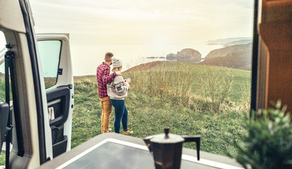 Unrecognizable couple traveling in camper van looking coastline landscape in the morning. Selective...
