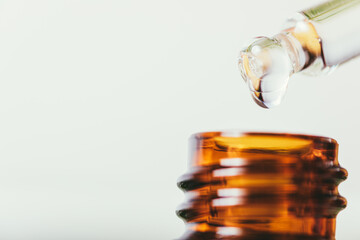 Essential oil drop from pipette into bottle