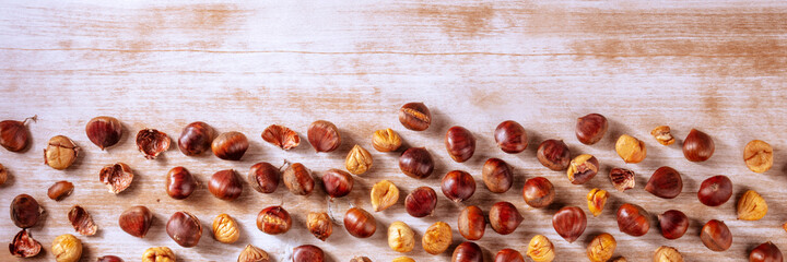 Baked chestnuts panorama, shot from the top on a rustic wooden background with copy space