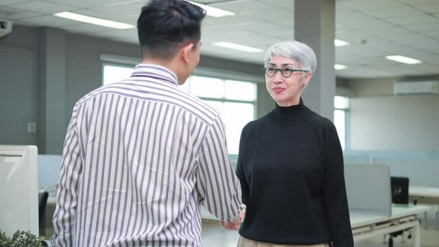 Asian businessman employee get appreciated promoted hired rewarded handshaking helpful senior female boss executive leader, in office as gratitude recognition thanks concept.