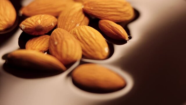 almonds dropping on a mirrorlike surface of liquid chocolate in slow motion (120fps)