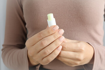 Woman holds hygienic lipstick, close up and selective focus