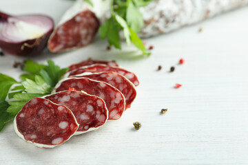 Сoncept of tasty food with salami sausage on white wooden background