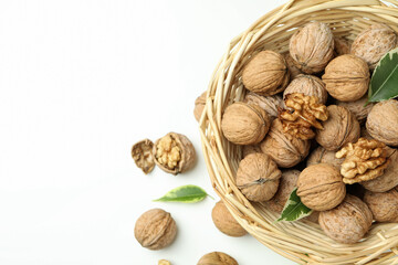 Walnuts in wicker bowl on white background