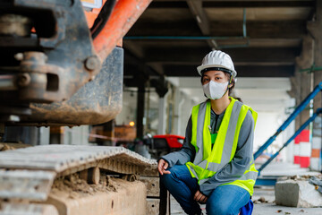 PORTRAIT, an Asian female engineer Wear a reflective vest and a white safety hat. Checking the machines at work construction site area