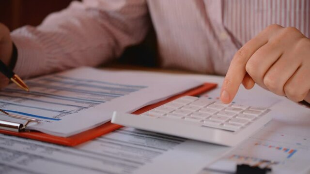 businessman working with financial statements and checks financial indicators on a calculator