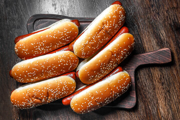 Hot dogs sprinkled with sesame seeds on a cutting board.