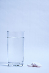 Glass of clean water and pills on a gray background.