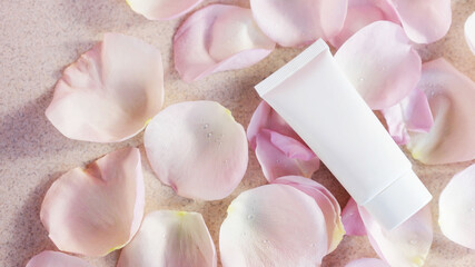 Cosmetic tube with face or body cream on a light background with rose petals. Anti aging care concept