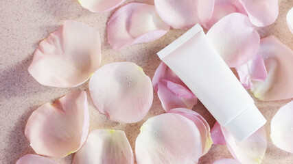 Cosmetic tube with face or body cream on a light background with rose petals. Anti aging care concept