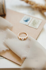 
Jewelry, engagement gold ring with sparkling white stone, diamond on a beige background. Selective...