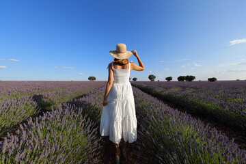 Woman walking holding hat in a lavender field
