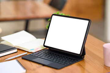 Fototapeta na wymiar Digital tablet blank white screen with keyboard on wooden table. Mock up.