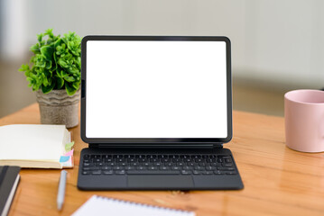 Fototapeta premium Digital tablet blank white screen with keyboard on wooden table. Mock up.