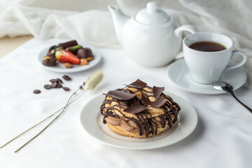 Chocolate choux pastry Rings with Cream Filling and cup of tea on the table
