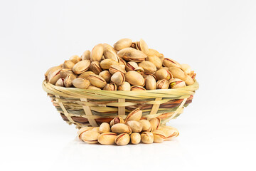 Pistachios in a small plate with scattered nuts of almonds around a plate on a vintage wooden table as a background. Pistachio is a healthy vegetarian protein nutritious food. Natural nuts snacks.
