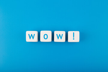 Wow single word on white toy cubes against bright blue background with copy space
